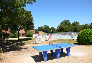 Tavolo da ping pong all'aperto vicino a una piscina recintata al Camping le Roc, Occitanie, Francia.