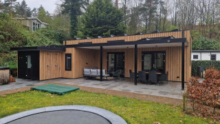 Udendørsbillede af Wellness Cottage 6p på De Thijmse Berg i Holland med træfacade og stor terrasse.