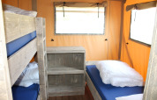 Indretning af en safari-telt med køjeseng og enkeltseng på Camping Sevink Molen, Nederlandene.