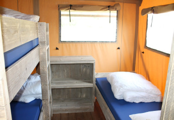 Interior de una tienda safari con literas y cama individual en Camping Sevink Molen, Países Bajos.