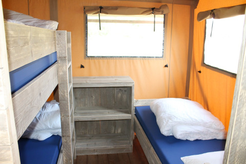 Interior de una tienda safari con literas y cama individual en Camping Sevink Molen, Países Bajos.