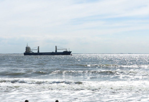 Zicht op de zee in Dishoek, Zeeland, Nederland, met een schip en zonlicht dat de golven verlicht.