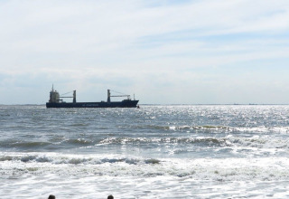 Zicht op de zee in Dishoek, Zeeland, Nederland, met een schip en zonlicht dat de golven verlicht.