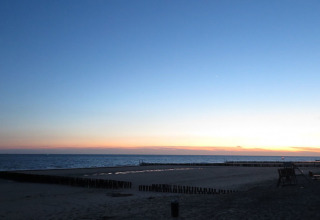 Sonnenuntergang am Strand von Dishoek, Zeeland, mit ruhigem Meer und Ferienpark-Atmosphäre.