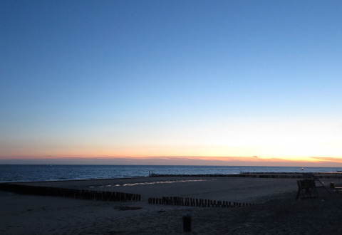Atardecer en la playa de Dishoek, Zelanda, con mar tranquilo y cielo sereno en un parque vacacional.