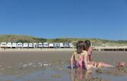 To børn leger i sandet foran strandhytter ved Welcome.in - Zeeland - Dishoek feriepark i Zeeland, Nederlandene.