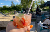 Hånd holder en sommerdrink med jordbær og is på Camping De La Vallée, Luxembourg, Belgien, udendørs.