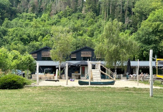 Playground and buildings at Camping De La Vallée, surrounded by greenery in Luxembourg, Belgium.