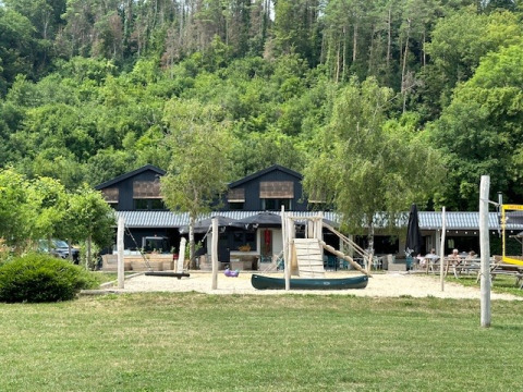Speelplein en gebouwen bij Camping De La Vallée, omringd door natuur in Luxemburg, België.