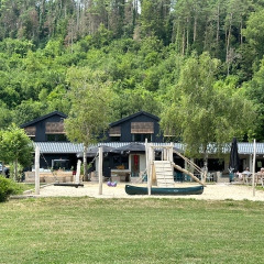 Spielplatz und Gebäude bei Camping De La Vallée, umgeben von Wald in Luxemburg, Belgien.