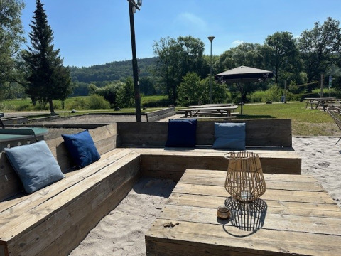Area salotto all'aperto con panche in legno al Camping De La Vallée, Lussemburgo belga, Belgio.