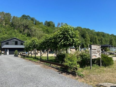 Vue du parc de vacances Camping De La Vallée en Belgique Luxembourg, entouré de verdure et ciel bleu.