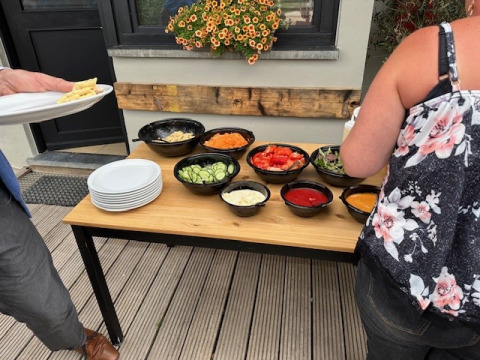 Mesa buffet al aire libre con varios vegetales e ingredientes de ensalada en Camping De La Vallée en Bélgica.