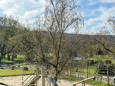 Parco giochi con sabbia e paesaggio verde al Camping De La Vallée, parco vacanze in Belgio Lussemburgo.