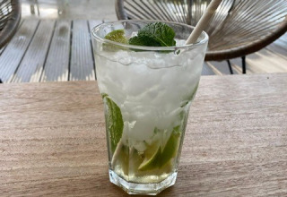 A mojito cocktail with mint and lime on a wooden table at Camping De La Vallée, Luxembourg, Belgium, outdoors.