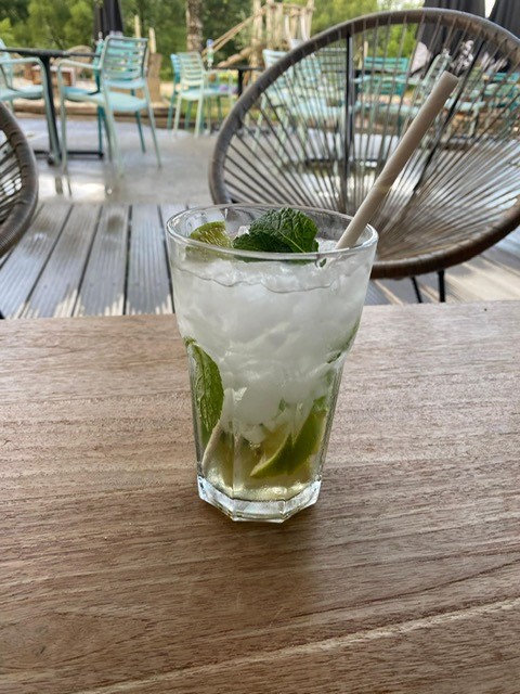 A mojito cocktail with mint and lime on a wooden table at Camping De La Vallée, Luxembourg, Belgium, outdoors.