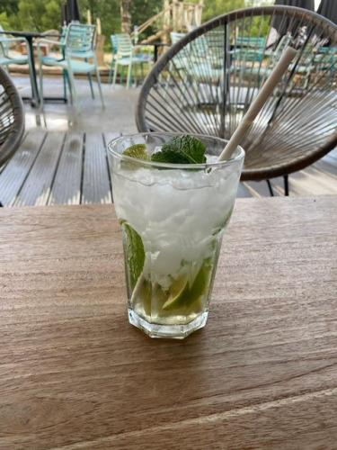 A mojito cocktail with mint and lime on a wooden table at Camping De La Vallée, Luxembourg, Belgium, outdoors.