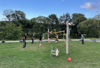 People playing volleyball outdoors on a grassy field at Camping De La Vallée, Belgium Luxembourg.