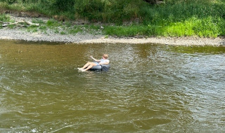Eine Person treibt entspannt auf einem Schwimmreifen auf einem Fluss in der Umgebung von Durbuy, Belgien.