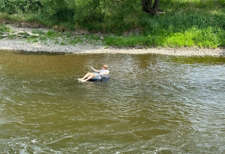 Eine Person treibt entspannt auf einem Schwimmreifen auf einem Fluss in der Umgebung von Durbuy, Belgien.
