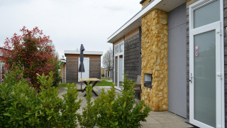Vista exterior del lodge Biebosch - tuinhuis en Resort Mooi Bemelen en los Países Bajos con jardín y terraza.