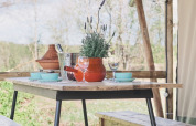 Rustieke houten tafel met banken en lavendelplant in een safaritent, gedekt voor een maaltijd.