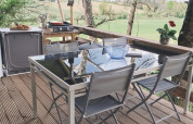 Zona de comedor al aire libre bajo carpa safari en Camping d'Artagnan, Francia, con vistas al campo.