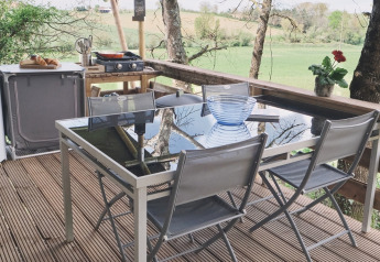 Zona pranzo all'aperto sotto tenda safari al Camping d'Artagnan in Francia con vista sulla natura.