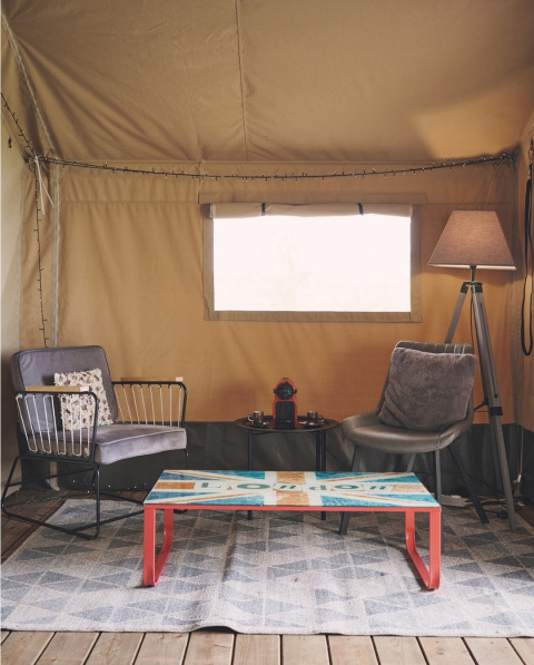 Gemütlicher Wohnbereich in einem Safarizelt auf Camping d'Artagnan in Frankreich, mit Sesseln und Tisch.