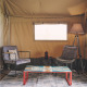Coin salon confortable dans une tente safari au Camping d'Artagnan en France, avec fauteuils et table colorée.