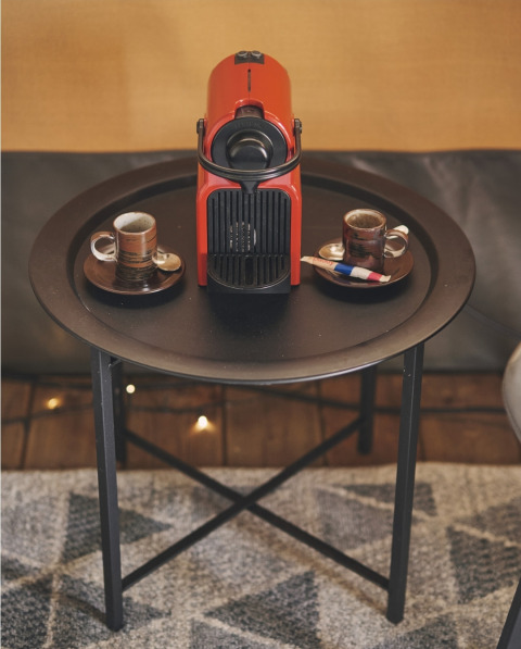 Rote Kaffeemaschine und zwei Espressotassen auf einem schwarzen Tisch im Safarizelt auf Camping d'Artagnan, Frankreich.