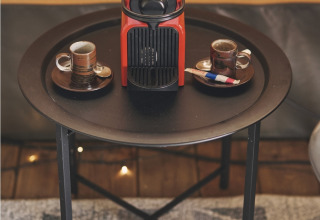 Red coffee machine and two espresso cups on a black table inside a safari tent at Camping d'Artagnan, France.