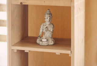 Estantería de madera en tienda safari con estatua de Buda, velas LED y juego de Scrabble en Francia.