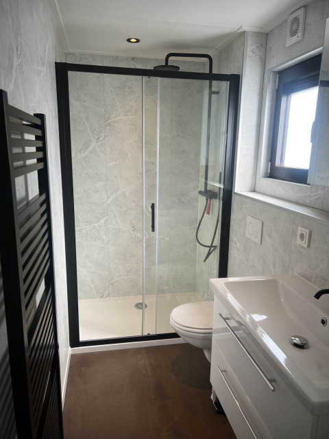 Modernes Badezimmer im Sea Pearl Chalet, Vakantiepark de Zeeuwse Parel, mit Duschkabine und Fenster.