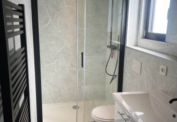 Modern bathroom in the Sea Pearl chalet at Vakantiepark de Zeeuwse Parel, with glass shower and sink.