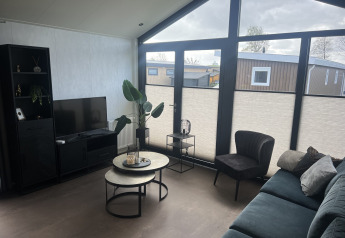 Stue i chalet Sea Pearl på Vakantiepark de Zeeuwse Parel, moderne møbler og store vinduer, Holland.