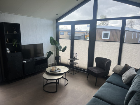 Stue i chalet Sea Pearl på Vakantiepark de Zeeuwse Parel, moderne møbler og store vinduer, Holland.