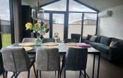 Moderne stue og spisestue i chalet Sea Pearl på Vakantiepark de Zeeuwse Parel med store vinduer.