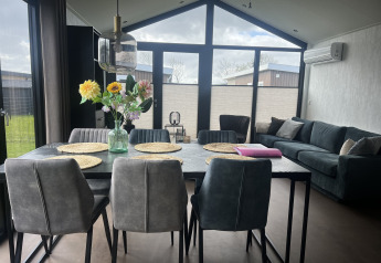 Moderne stue og spisestue i chalet Sea Pearl på Vakantiepark de Zeeuwse Parel med store vinduer.