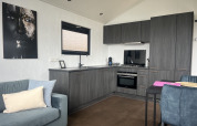 Moderne chaletkøkken og stue interiør med blå sofa og kunst på væggen i Sea Pearl på Vakantiepark de Zeeuwse Parel.