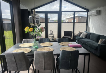 Moderne woon- en eetkamer met grote ramen in chalet Sea Pearl op Vakantiepark de Zeeuwse Parel in Nederland.