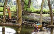 Kinder spielen auf einem Kletterspielplatz mit Holz und Seilen am Wasser im Beloofde Land, Gelderland.