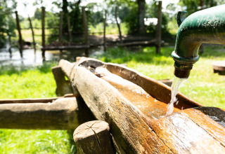Acqua che scorre da un rubinetto verde in una canalina di legno al Beloofde Land, Gelderland, Paesi Bassi.