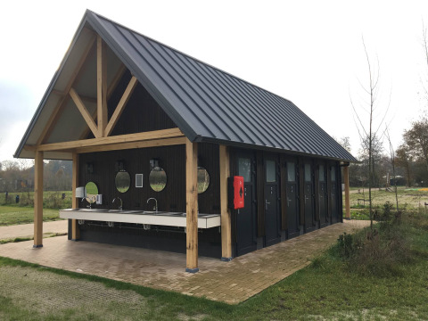 Et moderne servicehus med sort tag og træbjælker i ferieparken Beloofde Land i Gelderland, Holland.