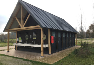 Et moderne servicehus med sort tag og træbjælker i ferieparken Beloofde Land i Gelderland, Holland.