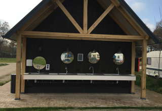 Espace de lavage extérieur avec quatre miroirs ronds et lavabos au parc de vacances Beloofde Land, Gelderland.