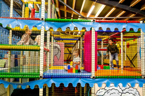 Niños jugando en una colorida zona de juegos cubierta del parque vacacional Beloofde Land en Gelderland, Países Bajos.