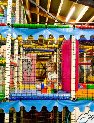 Niños jugando en una colorida zona de juegos cubierta del parque vacacional Beloofde Land en Gelderland, Países Bajos.