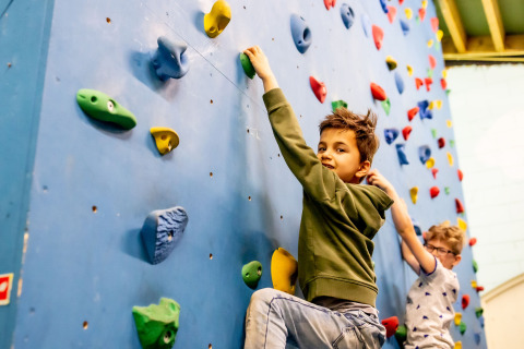 Two children climbing on an indoor climbing wall at Beloofde Land holiday park in Gelderland, Netherlands.