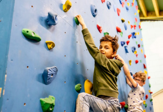 Two children climbing on an indoor climbing wall at Beloofde Land holiday park in Gelderland, Netherlands.